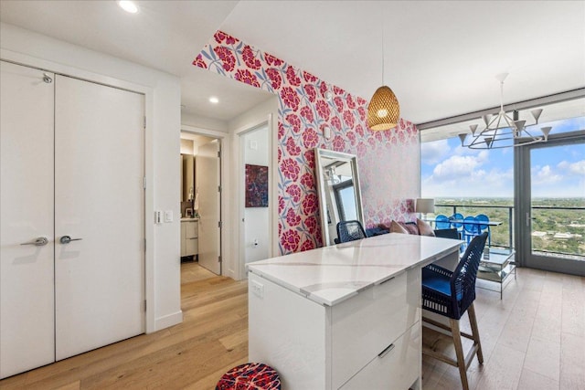 44 E Ave Unit 2509, Austin, TX 78701 - kitchen with light wood finished floors, wallpapered walls, a chandelier, white cabinets, and a kitchen island