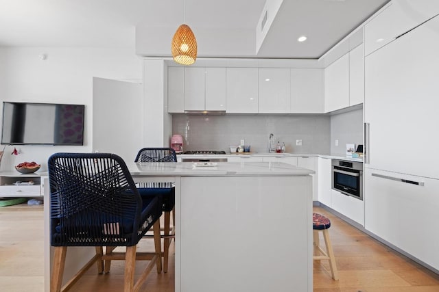 44 E Ave Unit 2509, Austin, TX 78701 - kitchen featuring modern cabinets, a breakfast bar area, oven, white cabinets, and light wood-style flooring