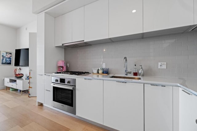44 E Ave Unit 2509, Austin, TX 78701 - kitchen featuring oven, modern cabinets, backsplash, and white cabinetry