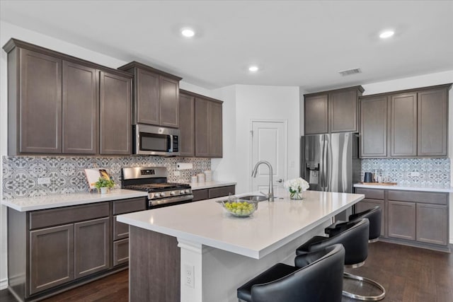 1007 Sandra Ann Way, Hutto, TX 78634 - kitchen with appliances with stainless steel finishes, a sink, dark brown cabinets, backsplash, and dark wood-type flooring