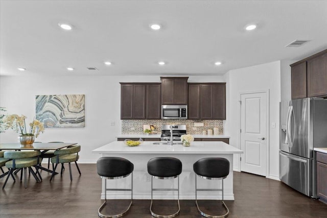 1007 Sandra Ann Way, Hutto, TX 78634 - kitchen featuring stainless steel appliances, light countertops, a breakfast bar area, dark wood-style floors, and recessed lighting