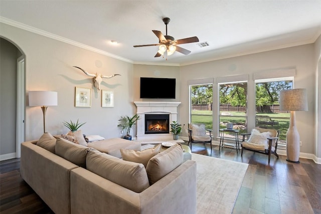 577 Shelf Rock Rd, Driftwood, TX 78619 - living room with ceiling fan, a lit fireplace, dark wood-type flooring, arched walkways, and crown molding