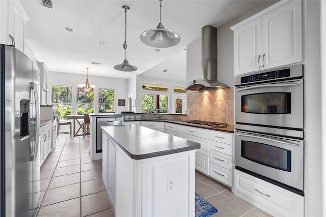 119 Maple Leaf Trl, Elgin, TX 78621 - kitchen featuring appliances with stainless steel finishes, wall chimney exhaust hood, a chandelier, decorative backsplash, and a peninsula