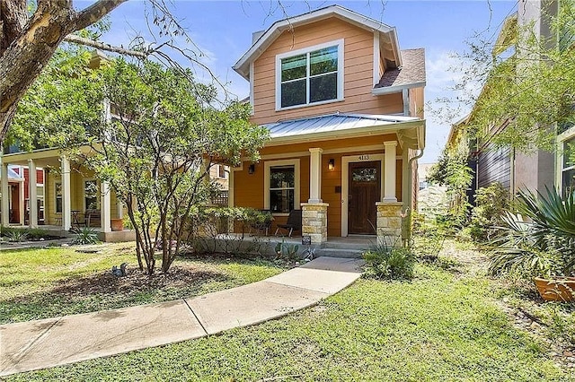 view of front of property with a standing seam roof, a front yard, metal roof, and covered porch