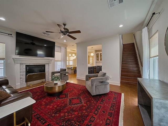 living room featuring visible vents, ceiling fan, stairway, and a fireplace