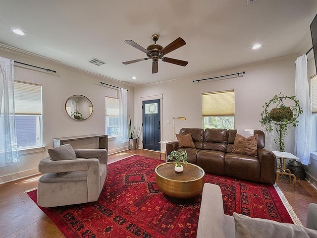 living room featuring crown molding, ceiling fan, baseboards, and visible vents