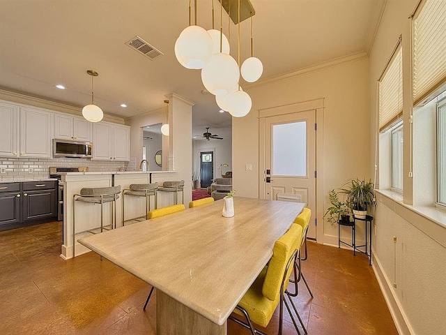 dining room with a wealth of natural light, visible vents, ornamental molding, and ceiling fan