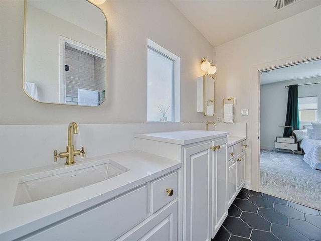 ensuite bathroom featuring visible vents, a sink, connected bathroom, two vanities, and tile patterned flooring