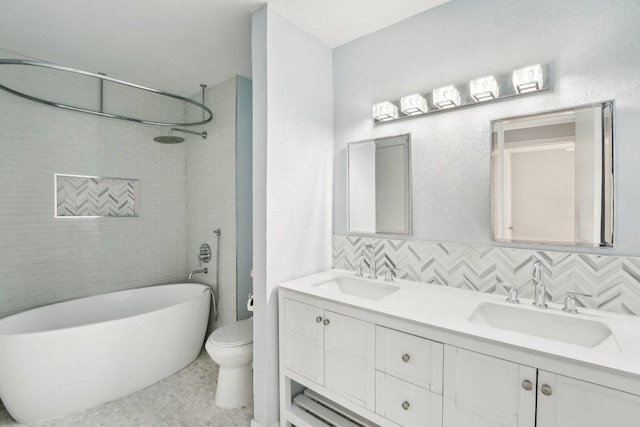 full bath with a sink, double vanity, toilet, and a freestanding tub