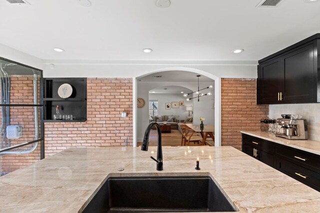 6009 Grover Ave, Austin, TX 78757 - kitchen featuring a sink, light stone counters, backsplash, dark cabinetry, and recessed lighting