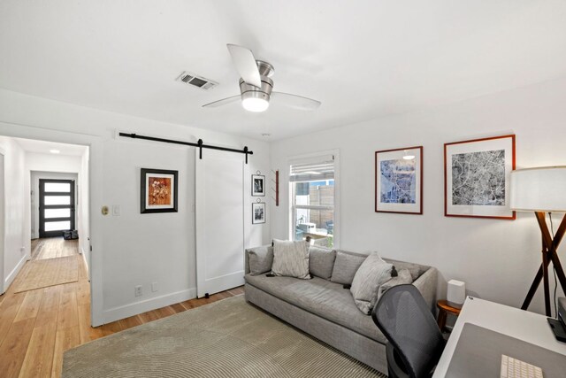 6009 Grover Ave, Austin, TX 78757 - living room featuring a barn door, light wood-style flooring, a ceiling fan, and baseboards