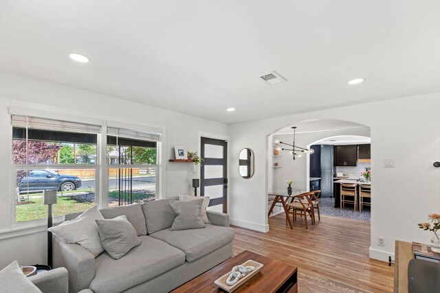 6009 Grover Ave, Austin, TX 78757 - living room with arched walkways, light wood finished floors, baseboards, recessed lighting, and a chandelier