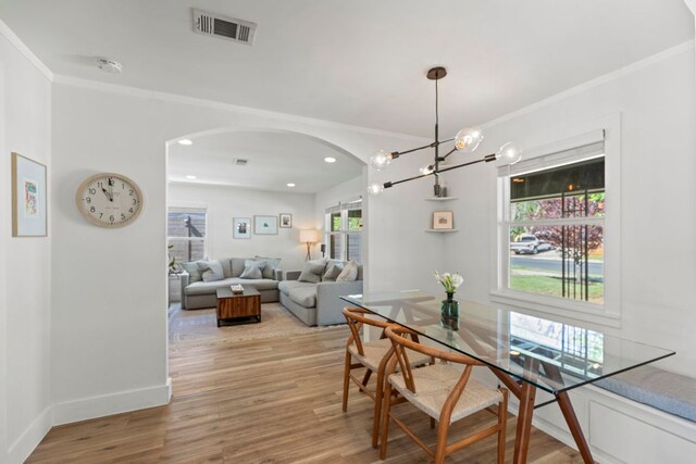 6009 Grover Ave, Austin, TX 78757 - dining area featuring arched walkways, light wood finished floors, crown molding, baseboards, and a chandelier