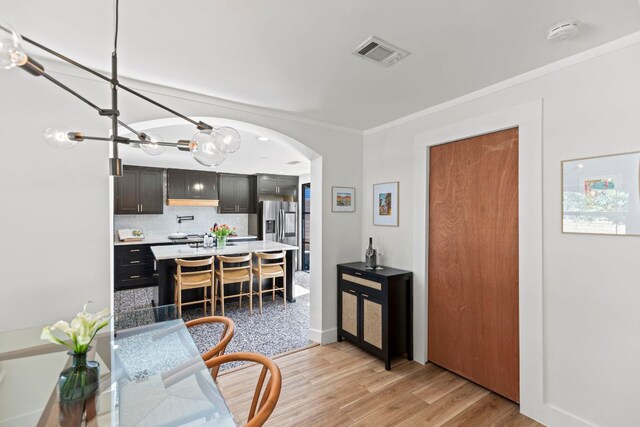 6009 Grover Ave, Austin, TX 78757 - kitchen featuring arched walkways, light countertops, crown molding, a chandelier, and tasteful backsplash