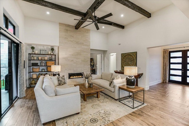 518 Doe Whisper Way, Austin, TX 78738 - living area with a towering ceiling, a tiled fireplace, wood finished floors, ceiling fan, and beamed ceiling