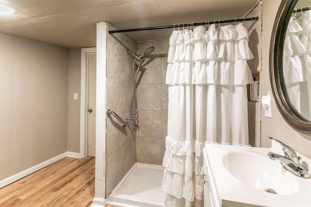 bathroom featuring vanity, baseboards, a stall shower, and wood finished floors
