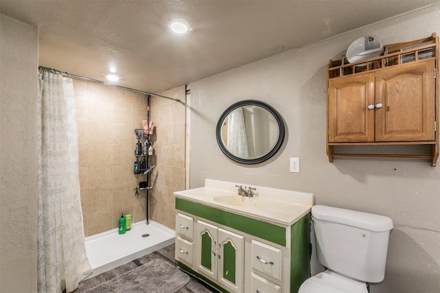 bathroom featuring toilet, tiled shower, and vanity