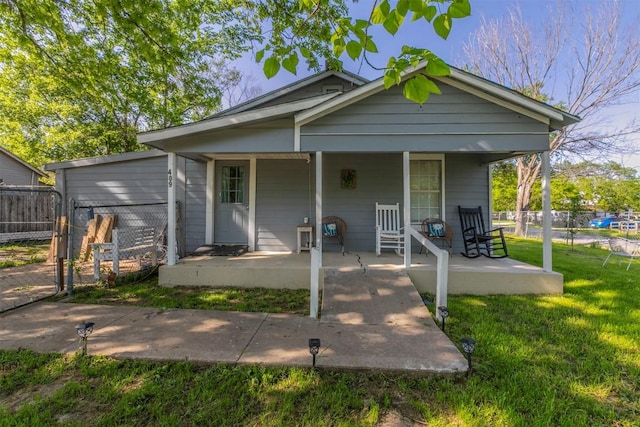 view of front of home with a porch, fence, and a front lawn