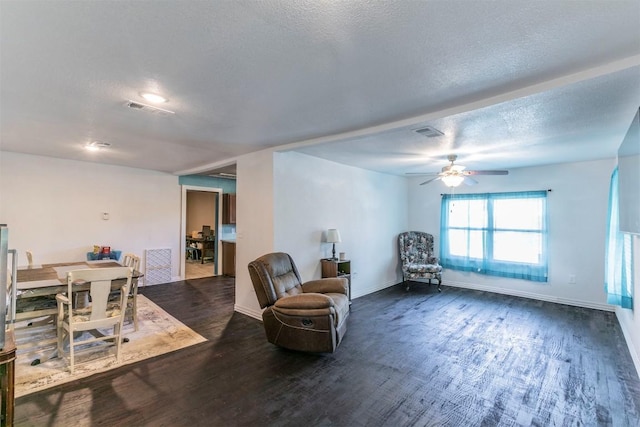 living area with dark wood-type flooring, visible vents, and a textured ceiling