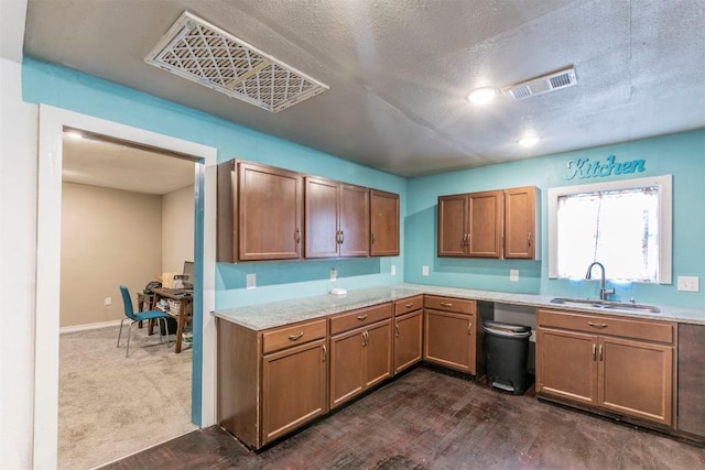kitchen with light countertops, brown cabinets, a sink, and visible vents