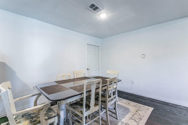 dining area featuring dark wood-type flooring, visible vents, and baseboards