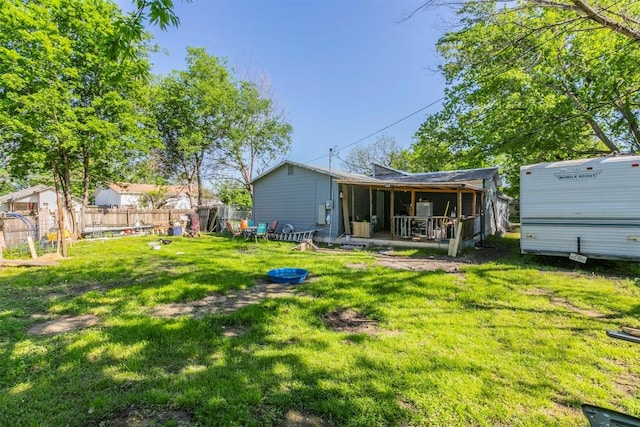 rear view of house featuring fence and a lawn