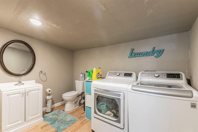 clothes washing area featuring independent washer and dryer, light wood-style floors, laundry area, and baseboards