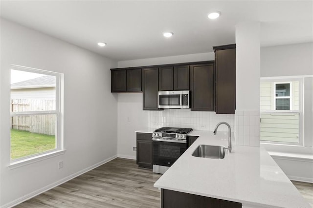 124 Rollingwood Dr, San Marcos, TX 78666 - kitchen with stainless steel appliances, a sink, dark brown cabinetry, decorative backsplash, and recessed lighting