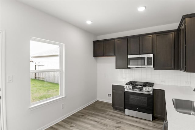 124 Rollingwood Dr, San Marcos, TX 78666 - kitchen featuring appliances with stainless steel finishes, light countertops, a sink, dark brown cabinetry, and recessed lighting