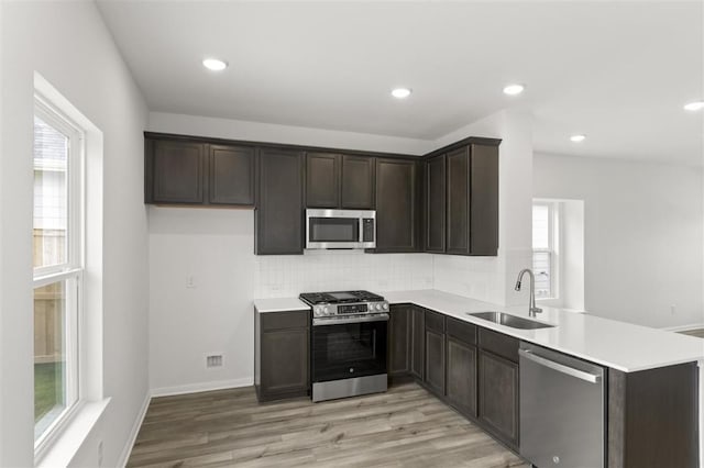 124 Rollingwood Dr, San Marcos, TX 78666 - kitchen with appliances with stainless steel finishes, a sink, a peninsula, backsplash, and light wood-type flooring