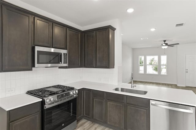 124 Rollingwood Dr, San Marcos, TX 78666 - kitchen with stainless steel appliances, a sink, dark brown cabinetry, light countertops, and decorative backsplash