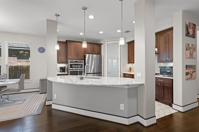 104 Atlanta Park Dr, Georgetown, TX 78628 - kitchen featuring appliances with stainless steel finishes, a sink, wood finished floors, light stone counters, and an island with sink
