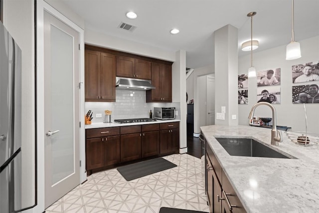 104 Atlanta Park Dr, Georgetown, TX 78628 - kitchen with a sink, under cabinet range hood, light floors, backsplash, and decorative light fixtures
