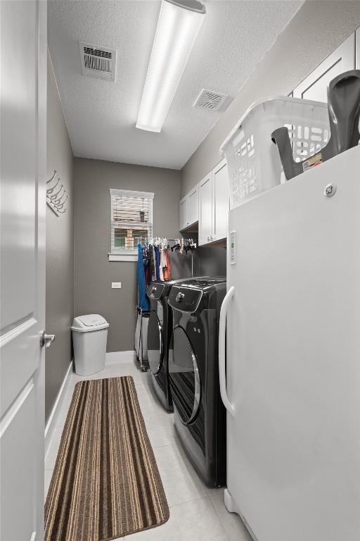 104 Atlanta Park Dr, Georgetown, TX 78628 - laundry area with cabinet space, independent washer and dryer, a textured ceiling, light tile patterned floors, and baseboards