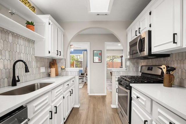 kitchen featuring white cabinetry, a sink, stainless steel appliances, light countertops, and backsplash