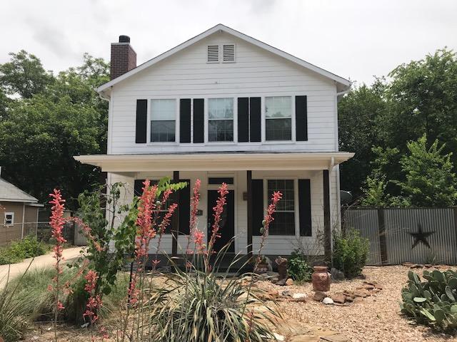 view of front of house featuring fence, a chimney, and covered porch