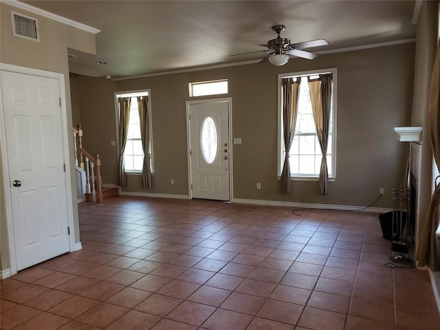 entryway with tile patterned floors, crown molding, and a healthy amount of sunlight