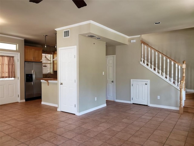 unfurnished living room featuring ornamental molding, visible vents, stairway, a sink, and baseboards