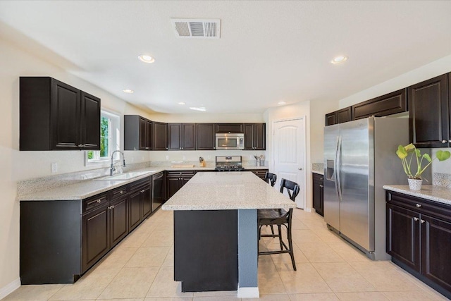 11208 Mickelson Dr, Austin, TX 78747 - kitchen featuring appliances with stainless steel finishes, a kitchen bar, a center island, light tile patterned floors, and recessed lighting