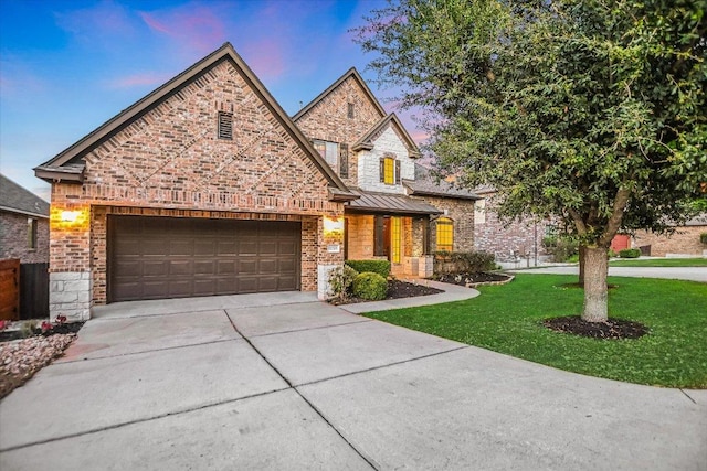 12325 Labrador Bay Ct, Austin, TX 78732 - view of front of home with driveway, a yard, an attached garage, a standing seam roof, and brick siding