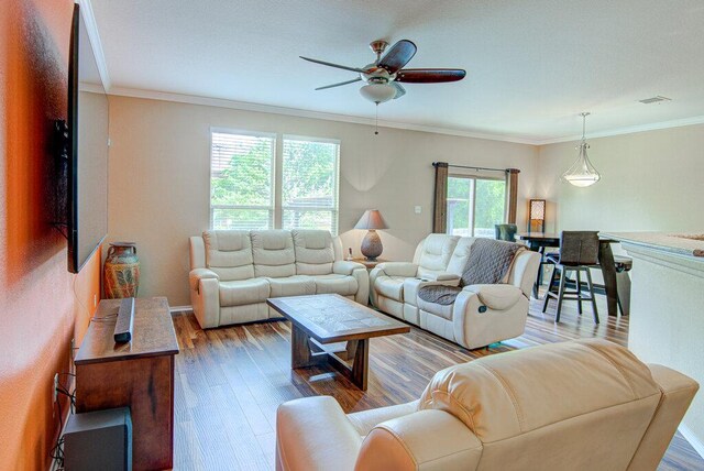living room featuring ceiling fan, ornamental molding, wood finished floors, and visible vents