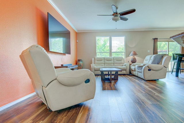 living area with baseboards, wood finished floors, ceiling fan, a textured wall, and ornamental molding