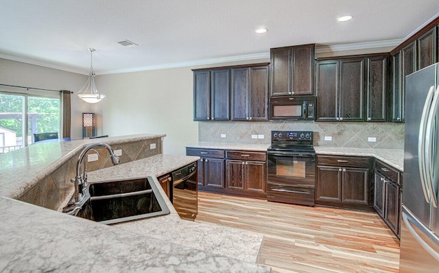 kitchen featuring light wood finished floors, a sink, pendant lighting, dark brown cabinetry, and black appliances