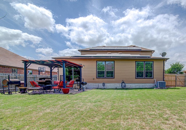 rear view of property featuring central AC unit, a pergola, a patio area, a lawn, and solar panels