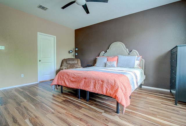bedroom featuring baseboards, a ceiling fan, wood finished floors, and visible vents