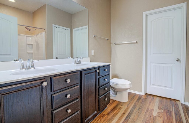 full bathroom featuring wood finished floors, a sink, double vanity, and toilet