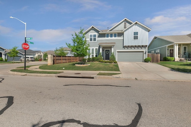 view of front of property with concrete driveway, board and batten siding, fence, and an attached garage