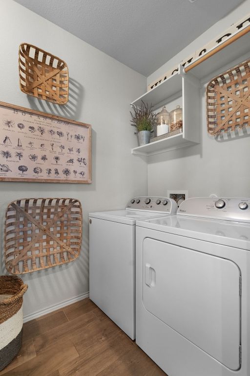 laundry area with independent washer and dryer, wood finished floors, laundry area, and baseboards
