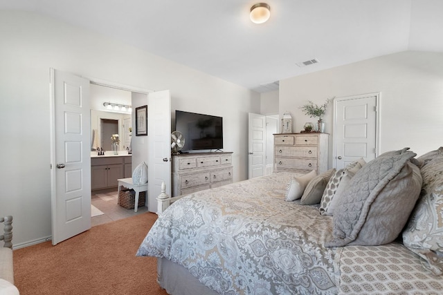 carpeted bedroom featuring ensuite bathroom, a sink, vaulted ceiling, and visible vents