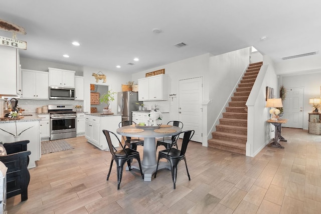 dining room with visible vents, baseboards, recessed lighting, stairs, and light wood-style flooring